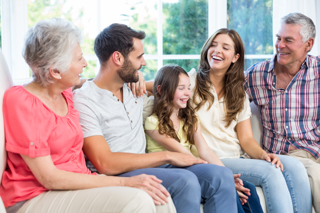 Multi-generation family smiling while sitting on sofa at home